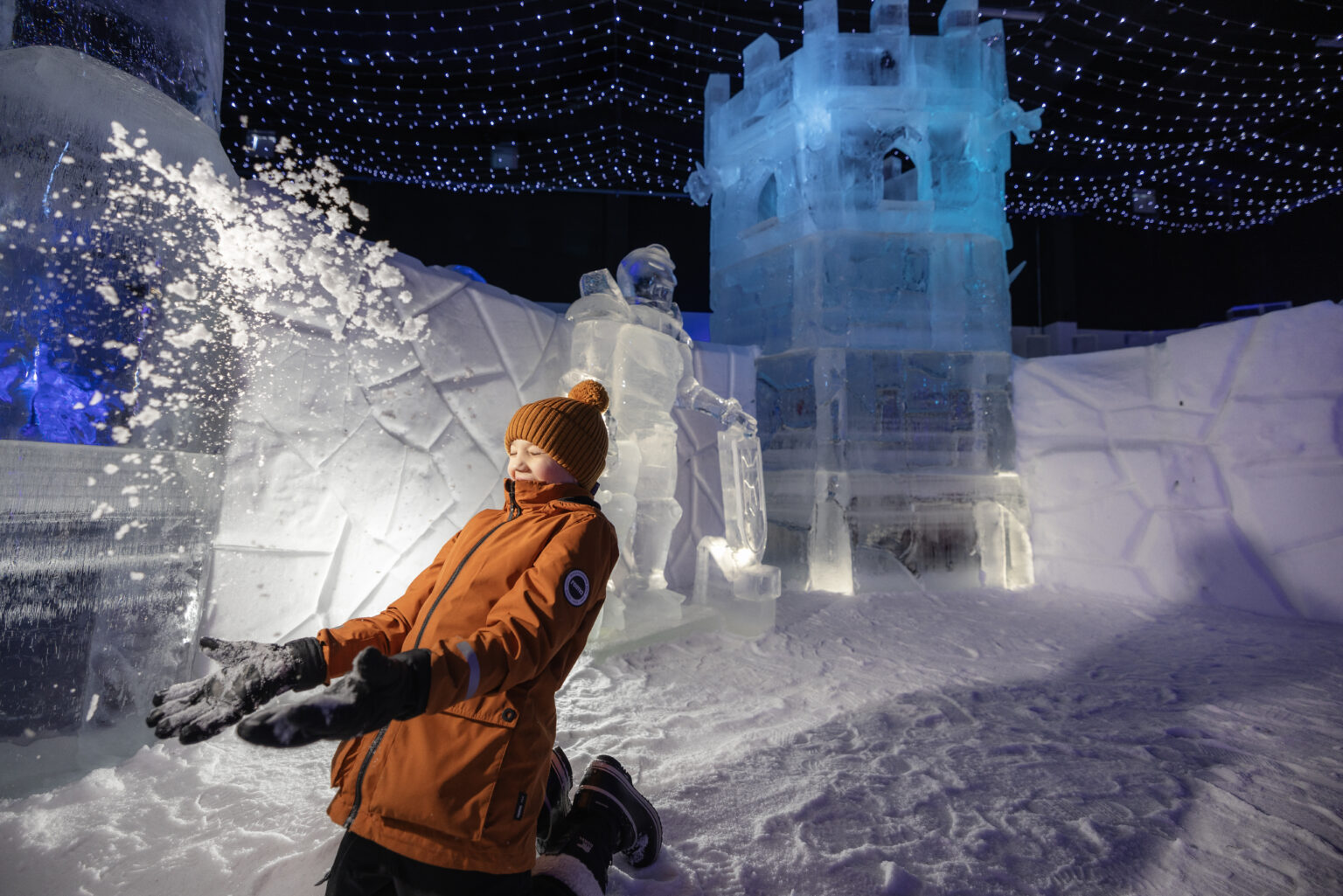 Packed snow walls and towers of a winter castle beside a frozen shore